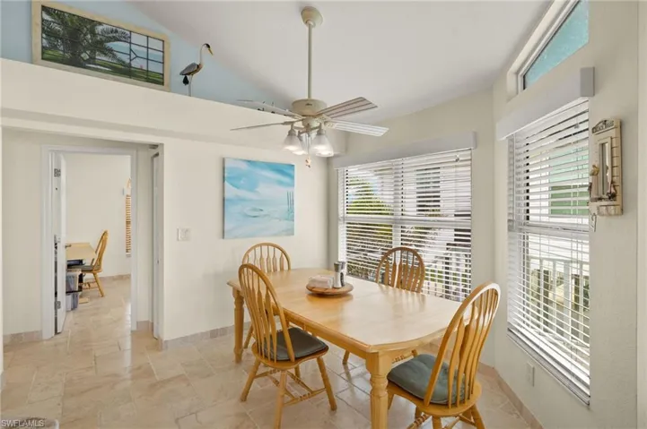 Dining room with a healthy amount of sunlight, baseboards, vaulted ceiling, and stone tile flooring