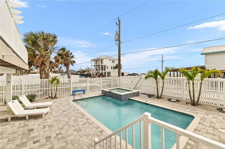 View of swimming pool featuring a fenced backyard, a pool with connected hot tub, and a patio