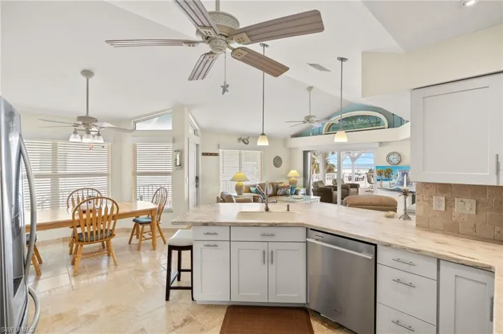 Kitchen featuring appliances with stainless steel finishes, a peninsula, a sink, vaulted ceiling, and backsplash