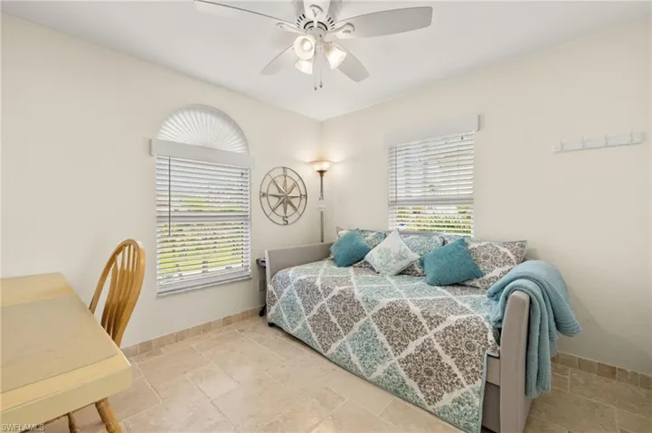 Bedroom with a ceiling fan, stone tile flooring, and baseboards