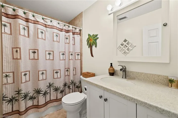 Bathroom with a shower with curtain, visible vents, vanity, and toilet