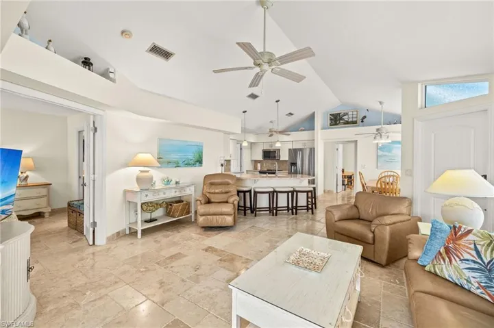 Living area with visible vents, vaulted ceiling, and ceiling fan