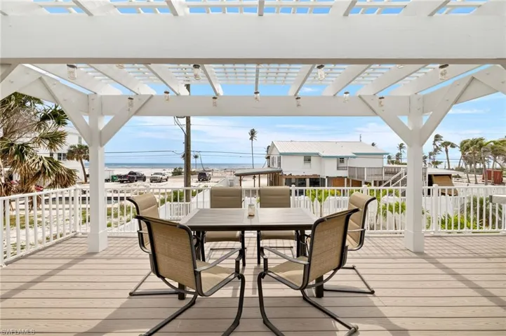 Wooden deck featuring outdoor dining area and a pergola