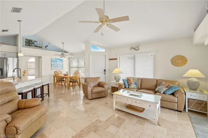 Living area with stone tile flooring, visible vents, and ceiling fan