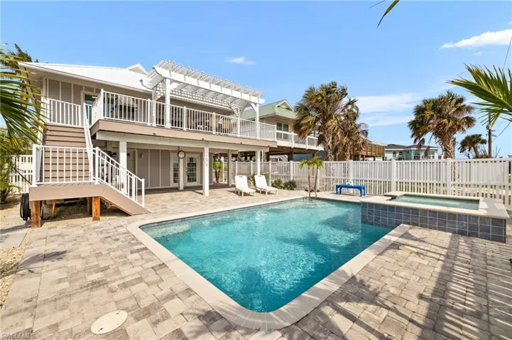 View of pool with a patio, fence, a pool with connected hot tub, stairs, and a pergola