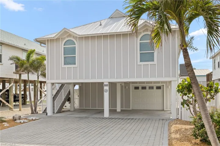 View of front of property featuring metal roof, decorative driveway, stairway, a carport, and board and batten siding
