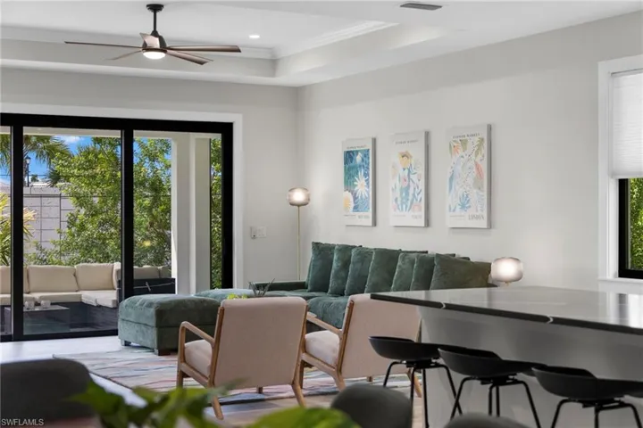 Spacious living area featuring a tray ceiling with recessed lighting and ceiling fan