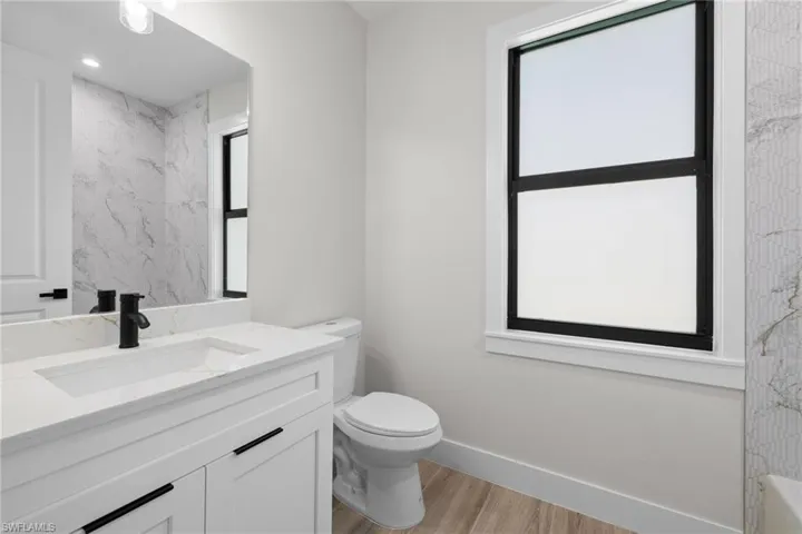 Bathroom featuring a white vanity with integrated sink, quartz-finish countertop, and matte black faucet