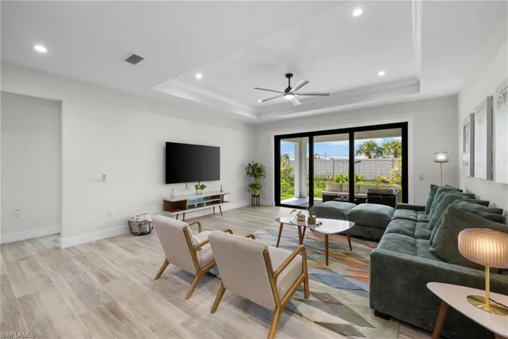 Living space featuring wood-finish flooring, recessed lighting, and a tray ceiling with a ceiling fan