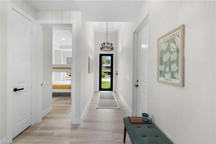 Entryway featuring wood-finish flooring, a modern drum pendant light, and a framed glass entry door