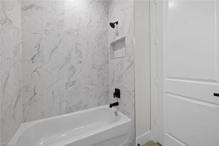 Bathtub with a matte black shower head and faucet, featuring a recessed niche