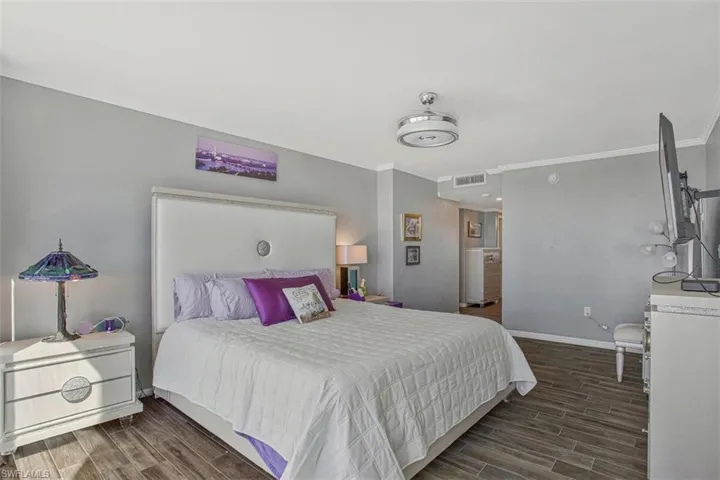 Bedroom with wood finish floors and crown molding