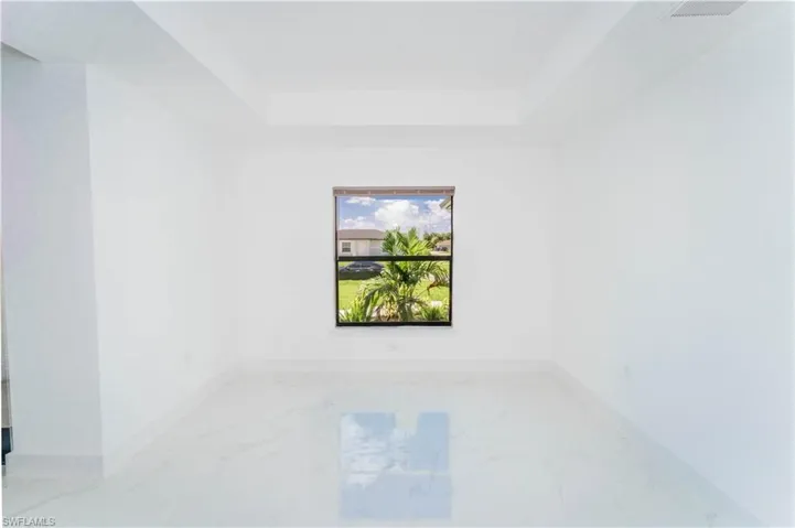 Spare room featuring a tray ceiling and marble finish floors