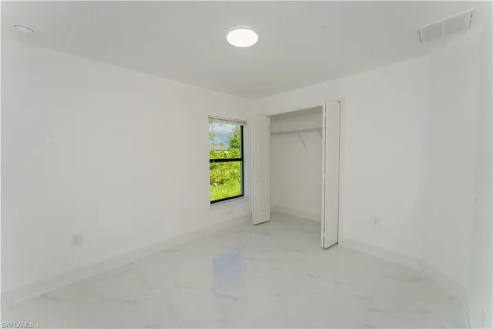 Unfurnished bedroom with light marble finish flooring and a closet