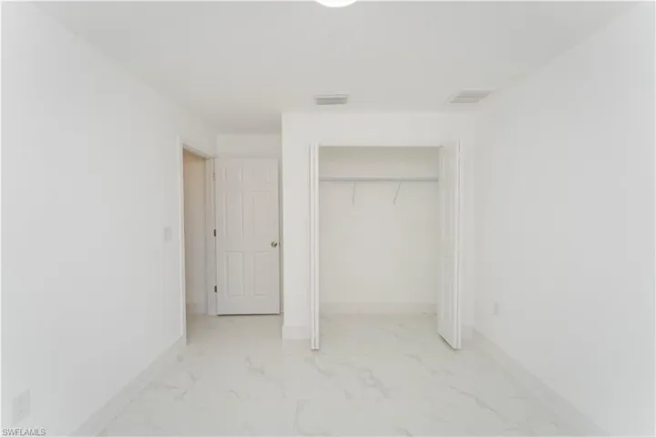 Unfurnished bedroom featuring light marble finish flooring and a closet