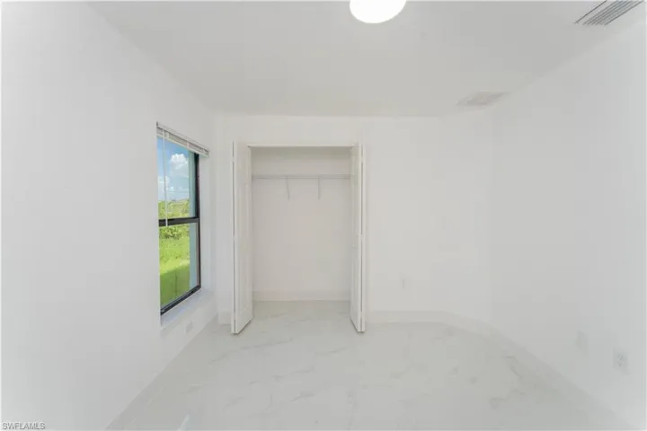 Unfurnished bedroom with light marble finish floors and a closet