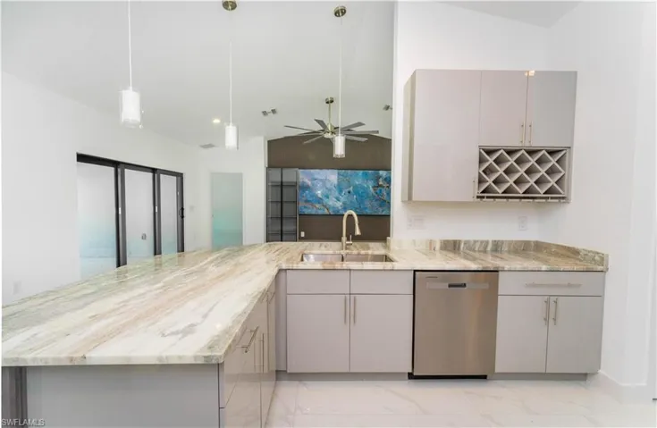 Kitchen featuring light marble finish floors, gray cabinetry, a ceiling fan, dishwasher, and a peninsula