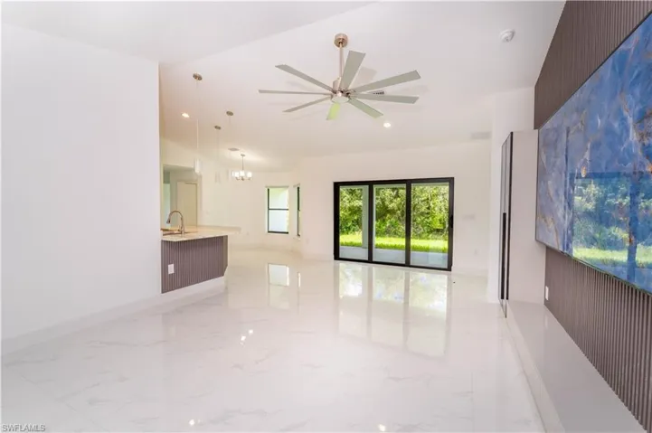 Empty room featuring light marble finish flooring, a ceiling fan, a chandelier, and recessed lighting