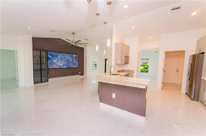 Kitchen featuring light marble finish flooring, a peninsula, ceiling fan, lofted ceiling, and freestanding refrigerator