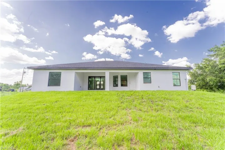 Rear view of house featuring stucco siding and a lawn