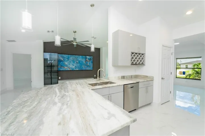 Kitchen featuring stainless steel dishwasher, light stone counters, a ceiling fan, pendant lighting, and recessed lighting
