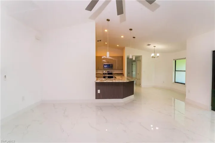 Kitchen featuring lofted ceiling, a ceiling fan, a chandelier, pendant lighting, and modern cabinets