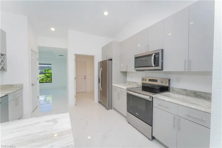 Kitchen featuring stainless steel appliances, light marble finish flooring, gray cabinetry, light countertops, and recessed lighting