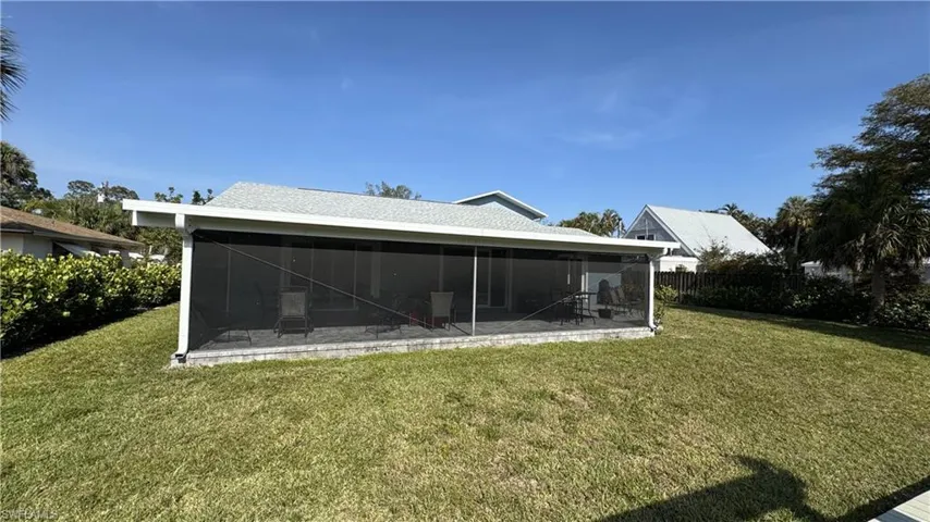 Rear view of property featuring a sunroom and a lawn