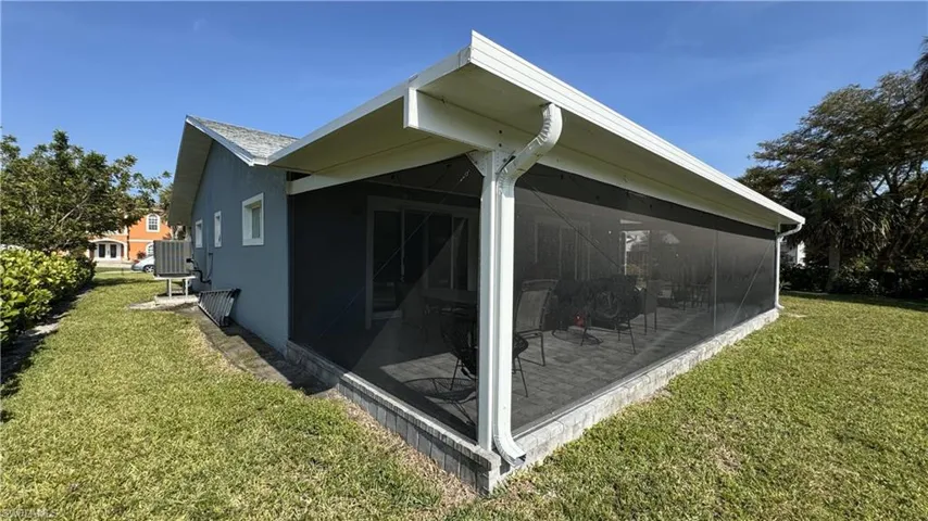 View of side of home with a sunroom and a yard