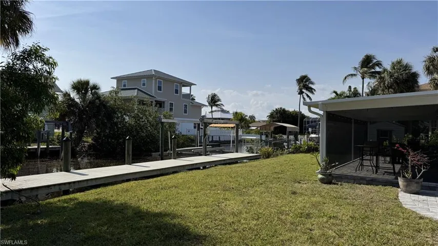 View of grassy yard featuring boat lift, a dock, and a residential view