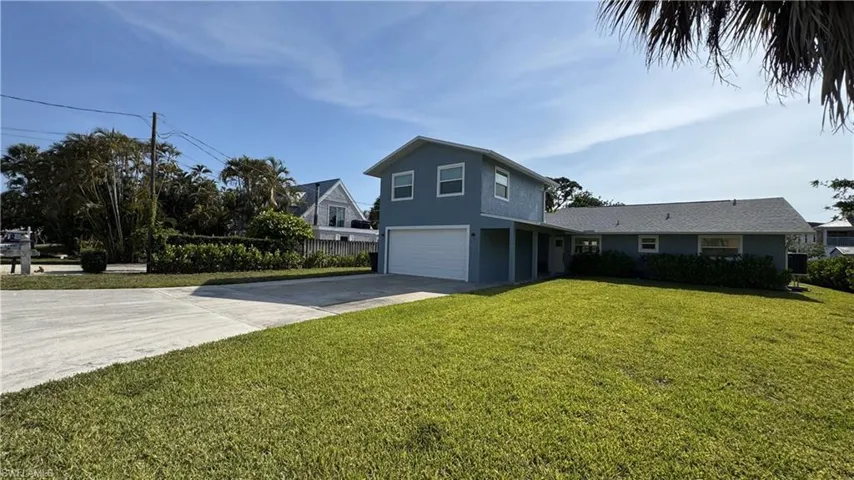View of side of property featuring a garage, concrete driveway, a yard, and stucco siding