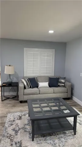 Living room with baseboards, wood finished floors, and recessed lighting