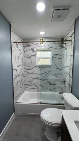 Full bathroom with vanity, toilet, shower / bathtub combination, and baseboards