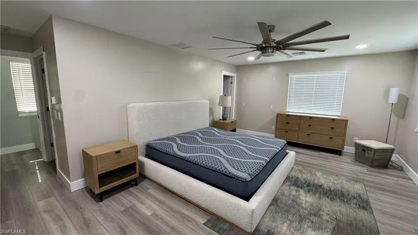 Bedroom with baseboards, light wood-type flooring, multiple windows, recessed lighting, and a ceiling fan