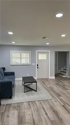 Living area with recessed lighting, wood finished floors, stairway, and baseboards