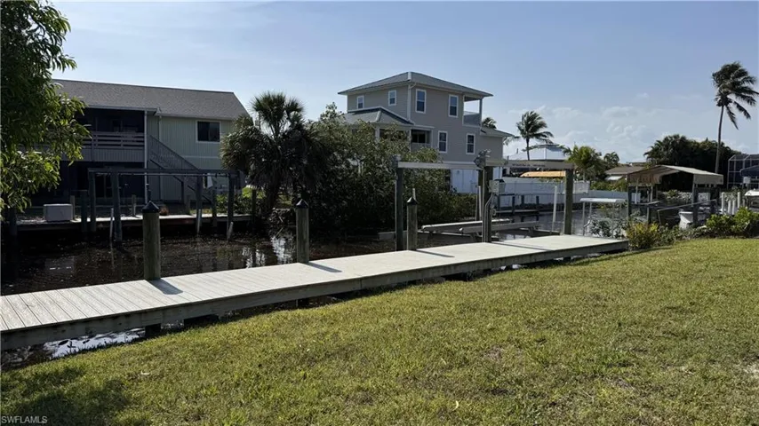 Dock area with boat lift, a water view, and a lawn