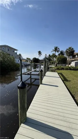 Dock featuring a water view, boat lift, and a yard