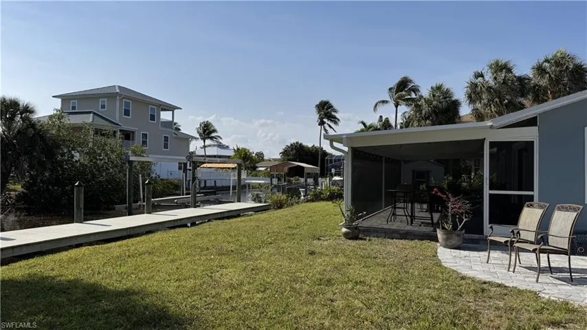 View of grassy yard featuring boat lift, a boat dock, and a sunroom