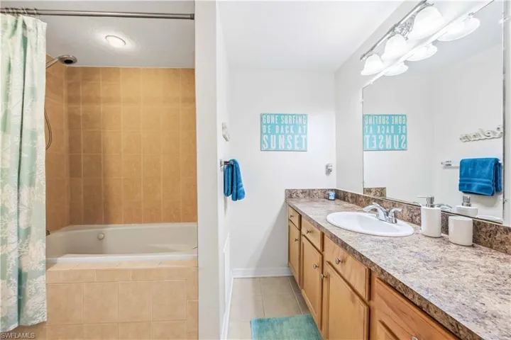 Full bathroom with tiled shower / bath, vanity, and light tile patterned flooring