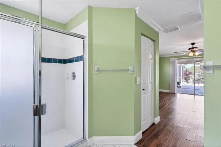 Bathroom featuring ceiling fan, an enclosed shower, hardwood / wood-style floors, and ornamental molding