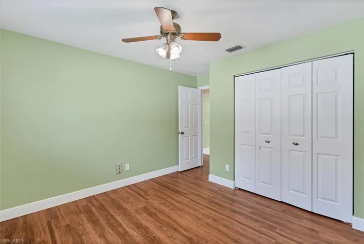 Unfurnished bedroom with dark hardwood / wood-style flooring, ceiling fan, and a closet