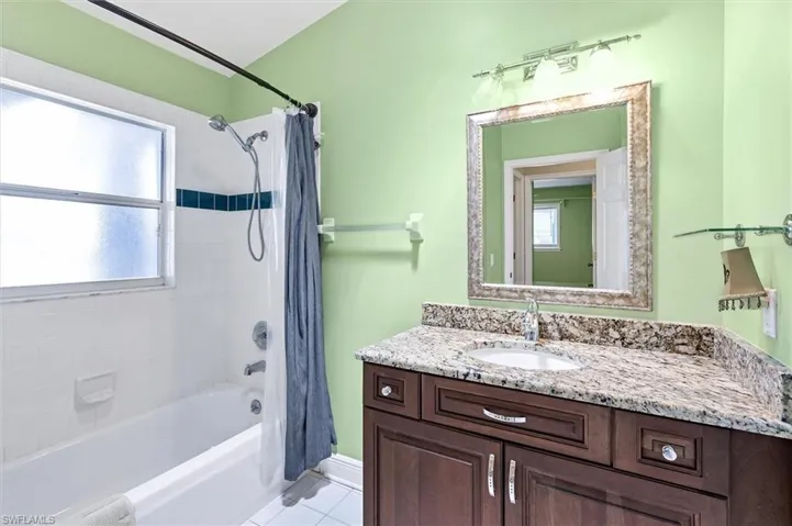 Bathroom with tile patterned flooring, vanity, and shower / bath combination with curtain