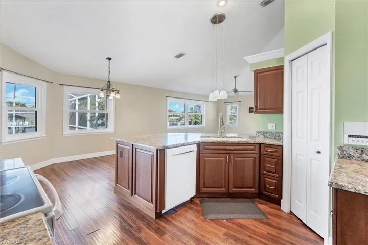 Kitchen with sink, white dishwasher, dark hardwood / wood-style floors, decorative light fixtures, and range