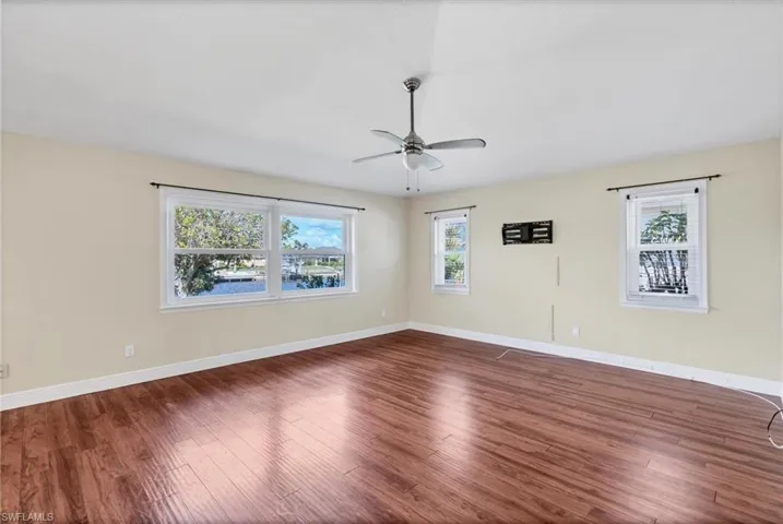 Spare room featuring a healthy amount of sunlight, dark hardwood / wood-style floors, and ceiling fan