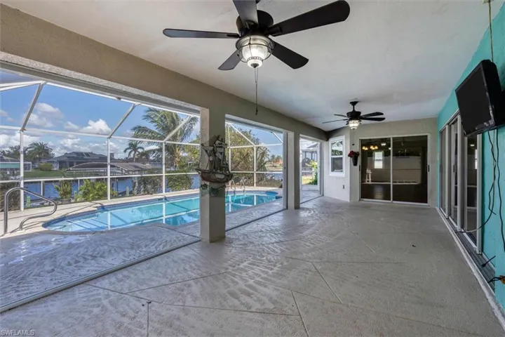 View of pool featuring a lanai, a water view, ceiling fan, and a patio