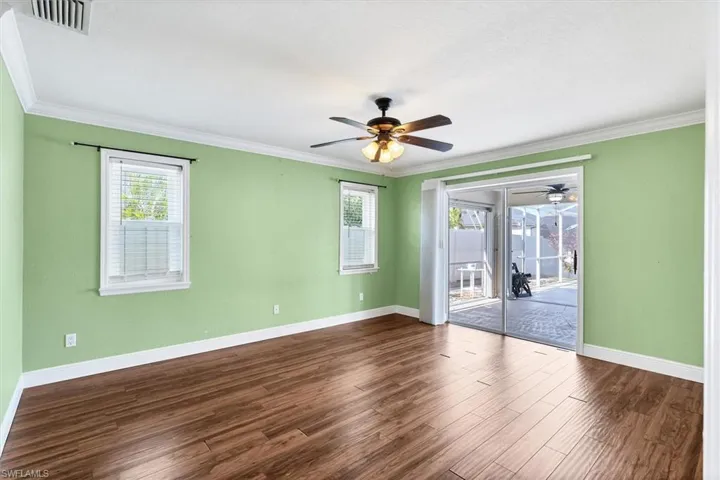 Spare room featuring dark wood-type flooring, ceiling fan, and ornamental molding