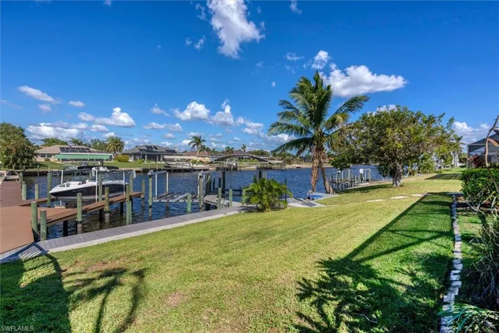View of dock with a lawn and a water view