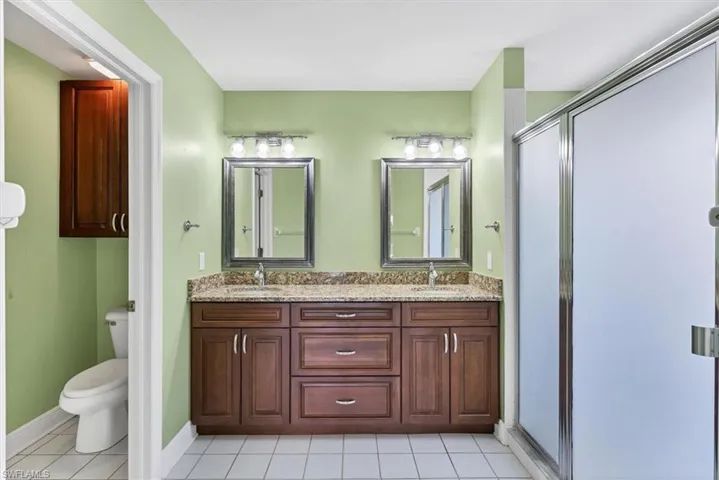 Bathroom featuring tile patterned flooring, an enclosed shower, vanity, and toilet