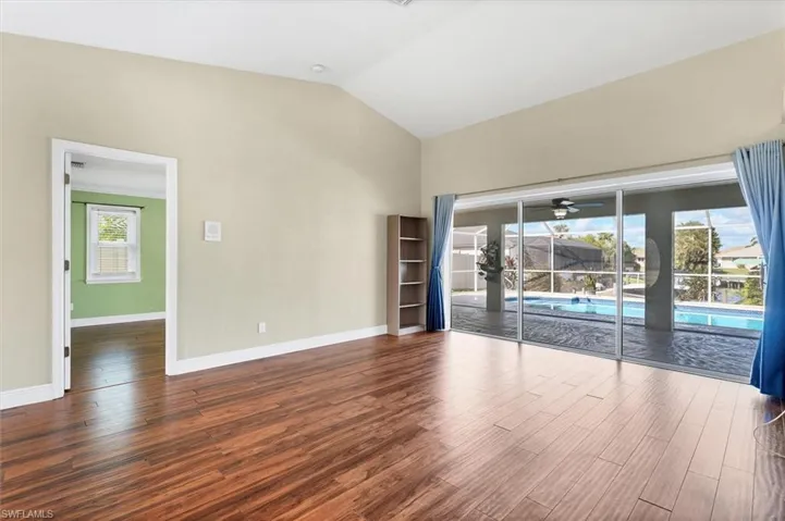 Unfurnished room with plenty of natural light, lofted ceiling, and hardwood / wood-style flooring