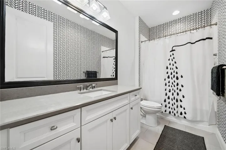 Bathroom with vanity with extensive cabinet space, tile flooring, and toilet